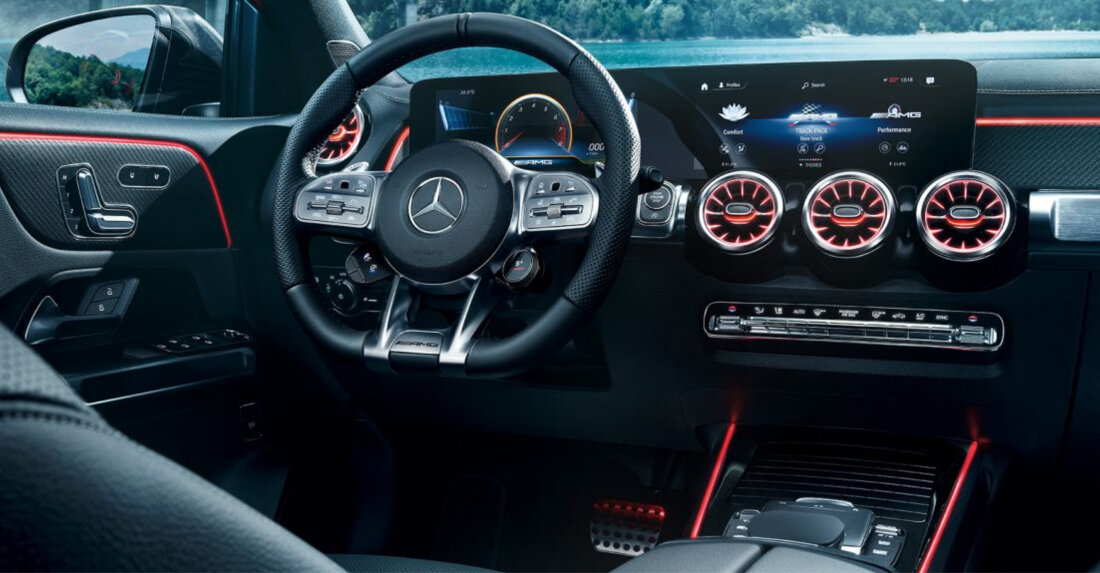 A Mercedes' dark interior with a stirring wheel and red highlights.