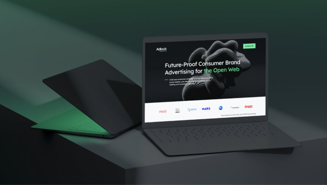 One of the two grey laptops is half-closed and gives off a green light. The other one is open on the Adlook main page. One of the two grey laptops is half-closed and gives off a green light. The other one is open on the Adlook main page.