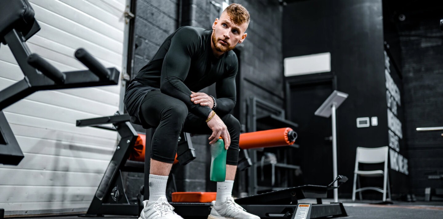 A man at a gym is sitting on a bench.