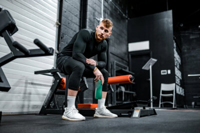 A man at a gym is sitting on a bench.