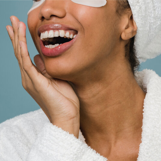 A young woman with eye pads smiling.