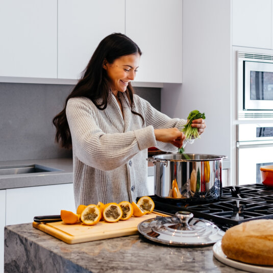 A young woman is cooking something in a big pot.