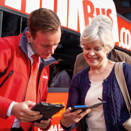 A passenger is showing their ticket to the Onnibus staff. A passenger is showing their ticket to the Onnibus staff.